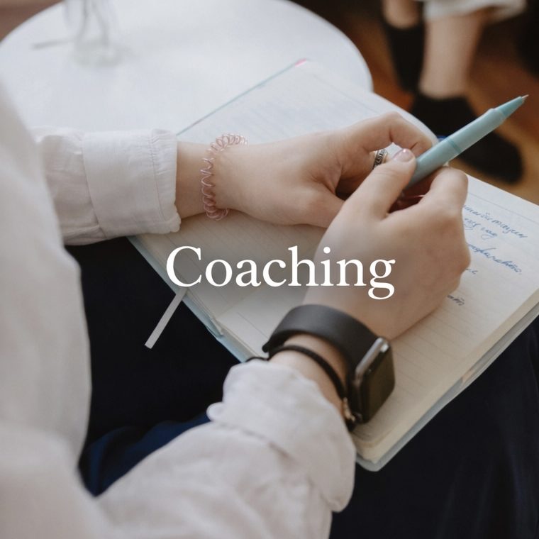 Kundenstimmen Hände halten einen Stift über einem Notizbuch mit der Aufschrift "Coaching".